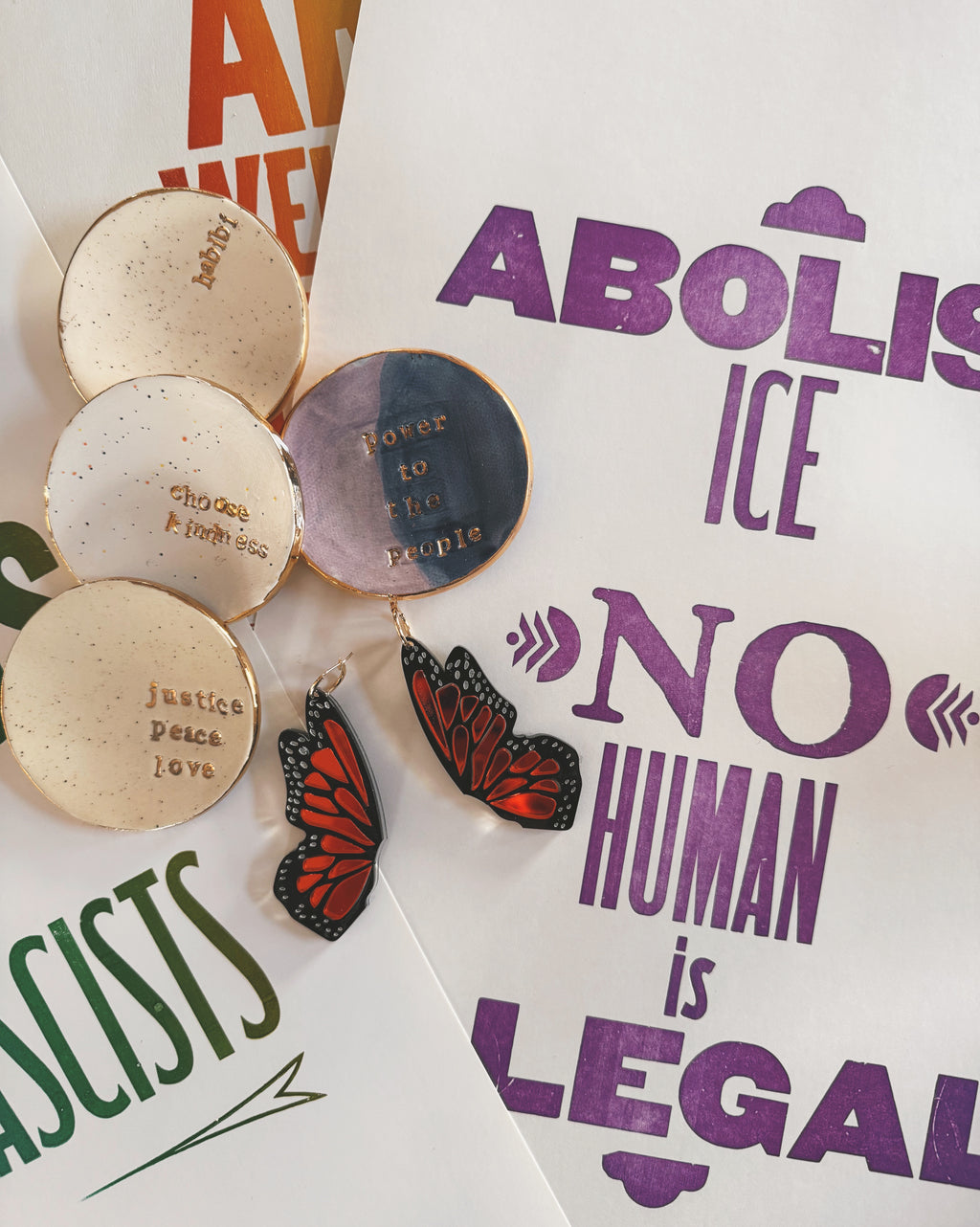 Medallions and butterfly earrings on a background with anti-racism posters