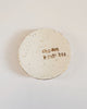 Round speckled ceramic dish with 'Choose Kindness' text held by a hand on a light background