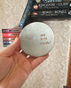 Round ceramic object with 'One More Chapter' engraved, held over books on a textured surface