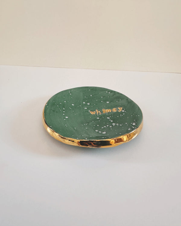 Green round dish with gold rim and whimsy stamped on a white background
